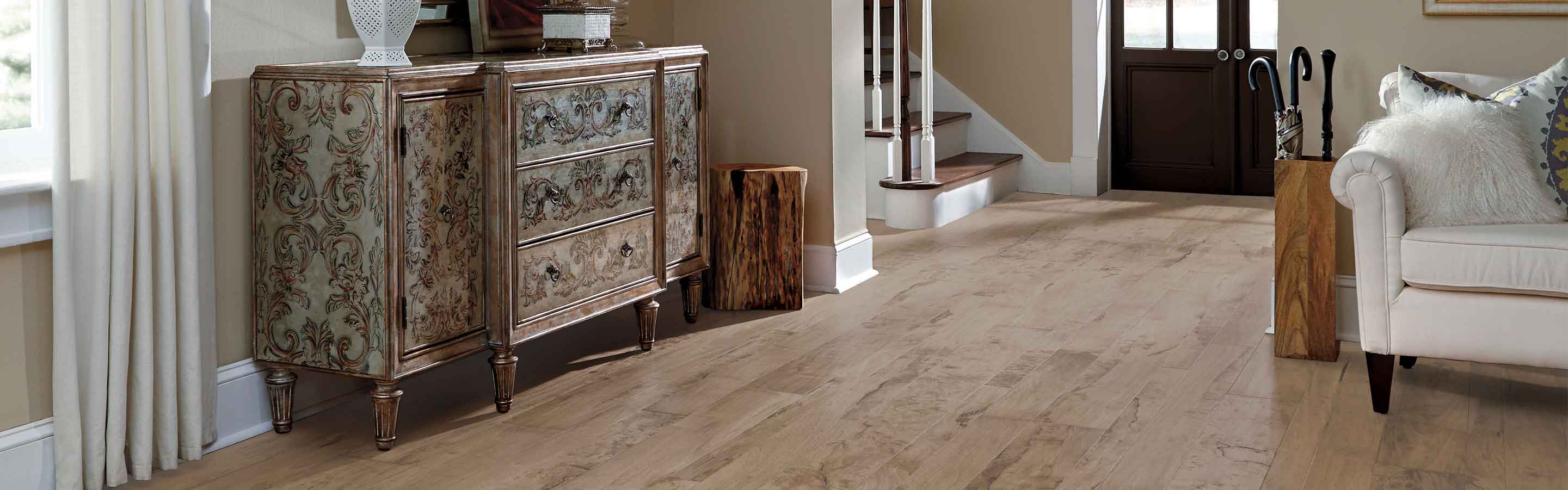 light hardwood flooring in entryway and with hardwood staircase and a white sofa in living area