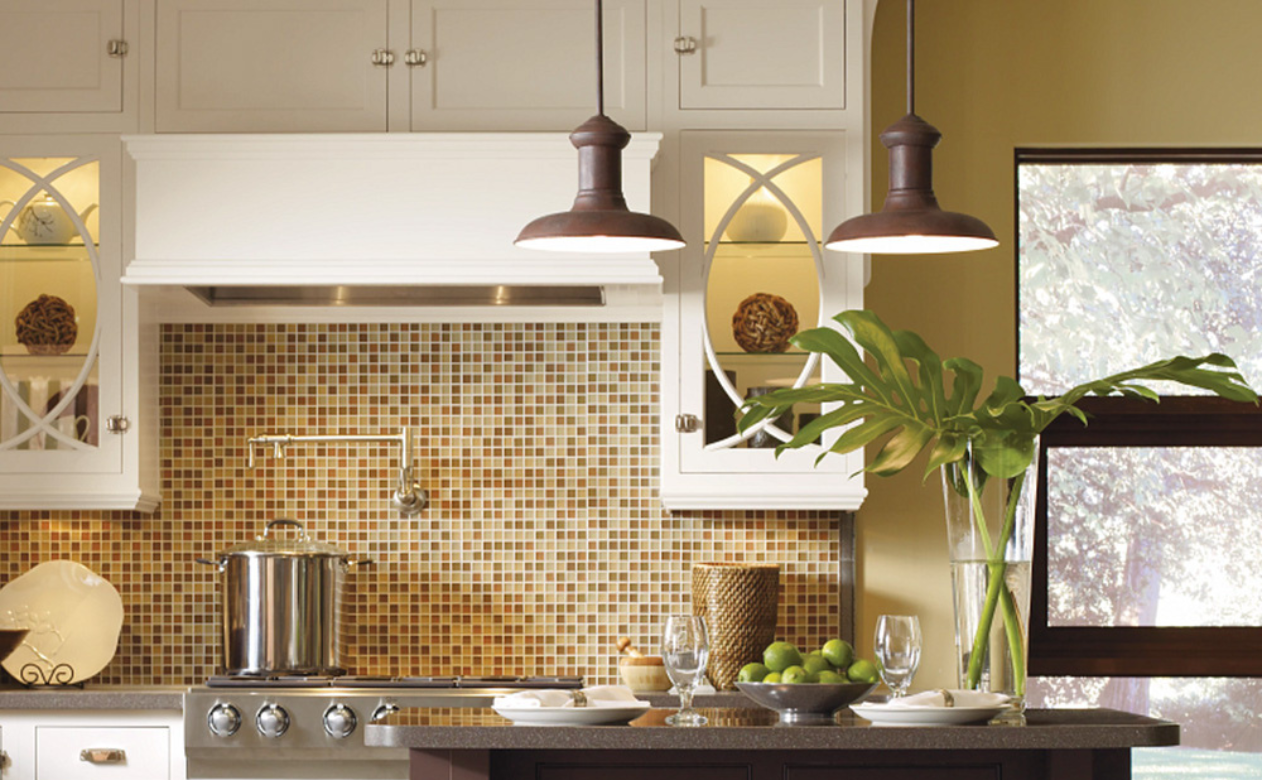 Modern kitchen with a mosaic backsplash, white cabinets, stainless steel appliances, and a dark island set with limes, plates, and brown ambient ceiling lights