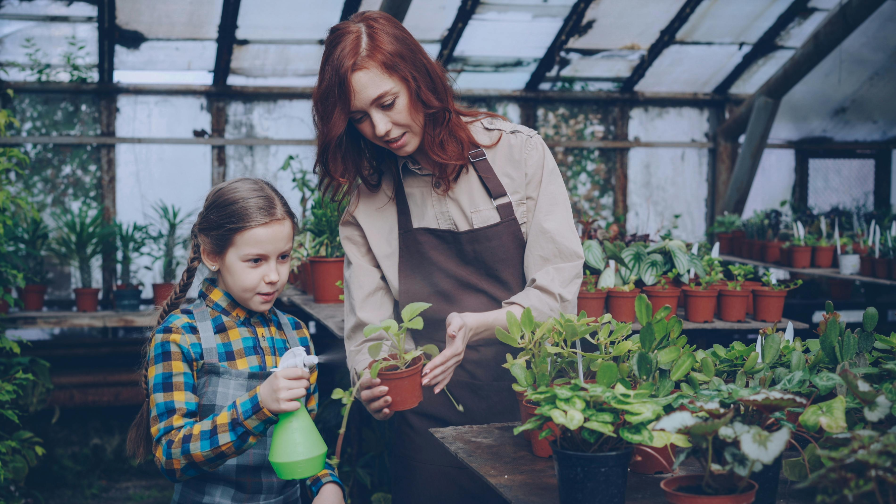 Mom & daughter work together in a greenhouse.